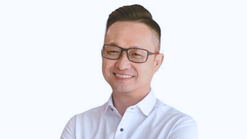 A man in white shirt is smiling while facing the camera