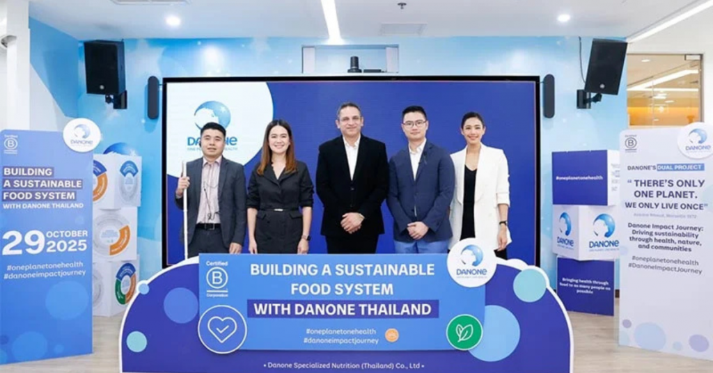 5 people was standing next to each other and facing the camera with a huge backdrop from Danone and the banner with title of "Building a sustainable food system" in front of them.